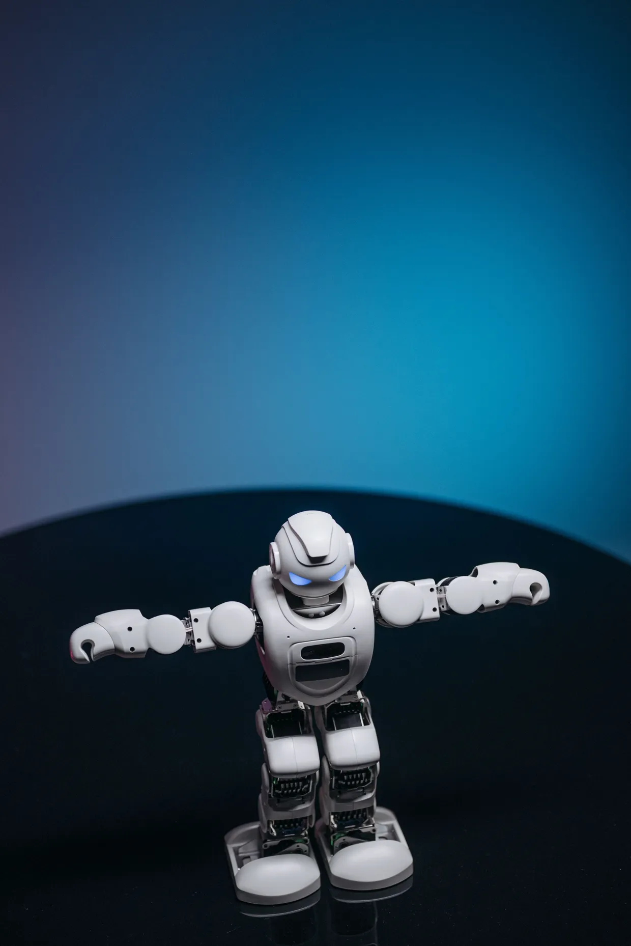 A small white humanoid robot with its arms outstretched